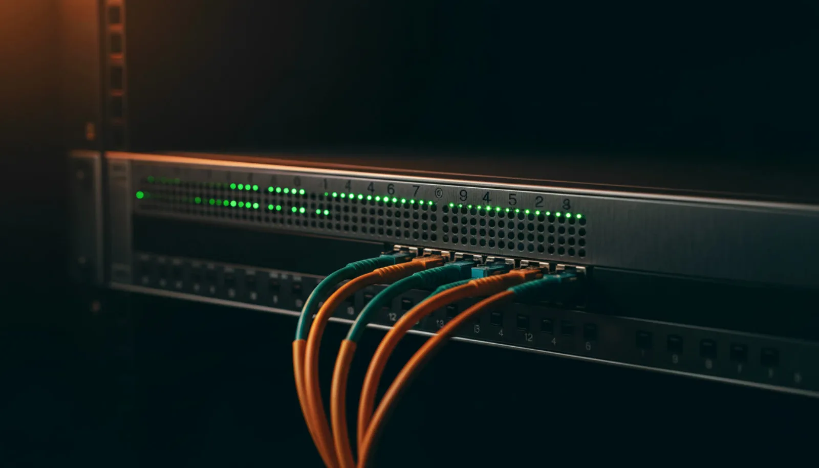 Green link lights across a rack-mounted switch, fiber patch cables running out of frame